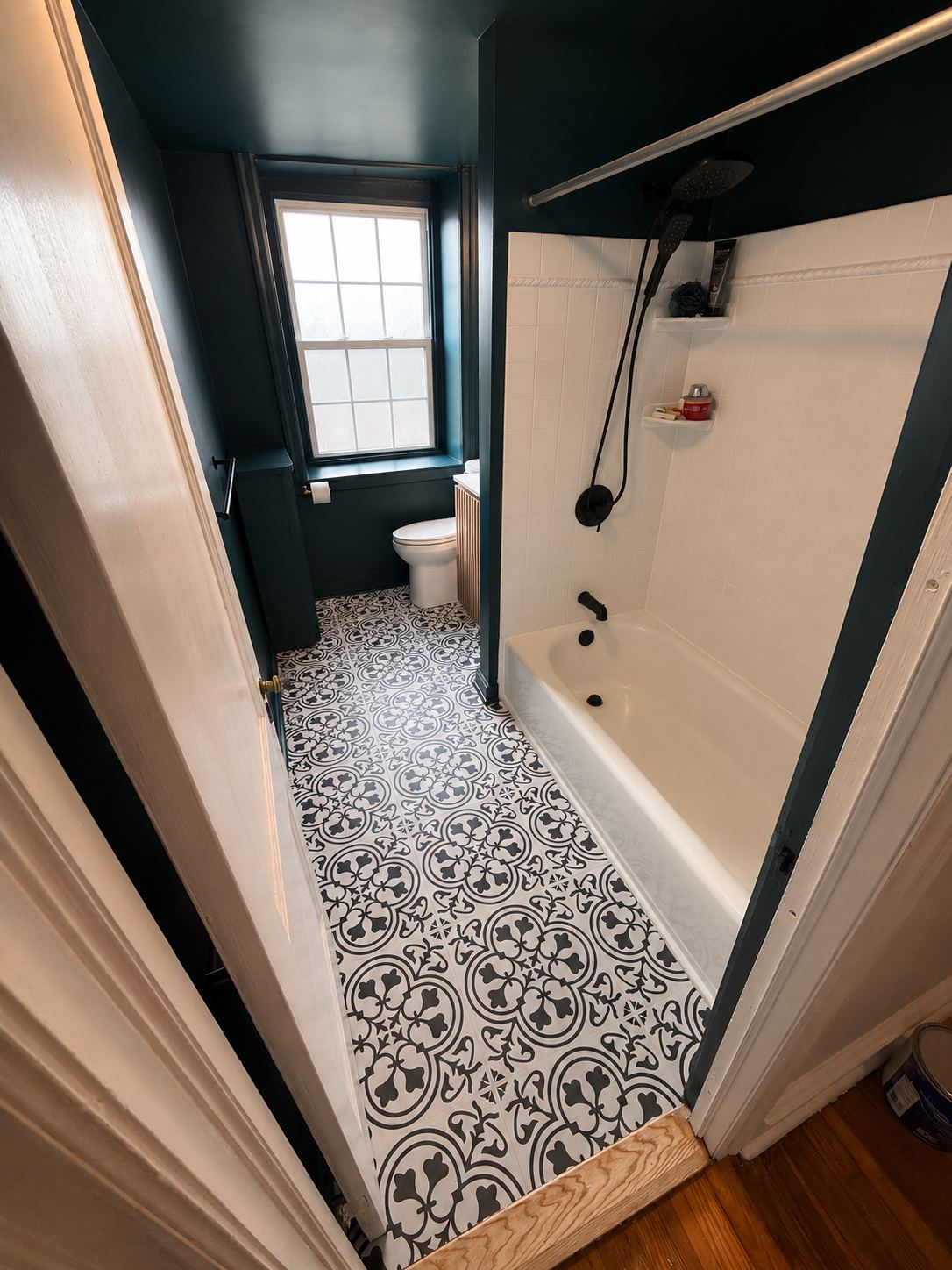 Bathroom after renovation showing new floor tile, fresh paint, and matte-black fixtures.