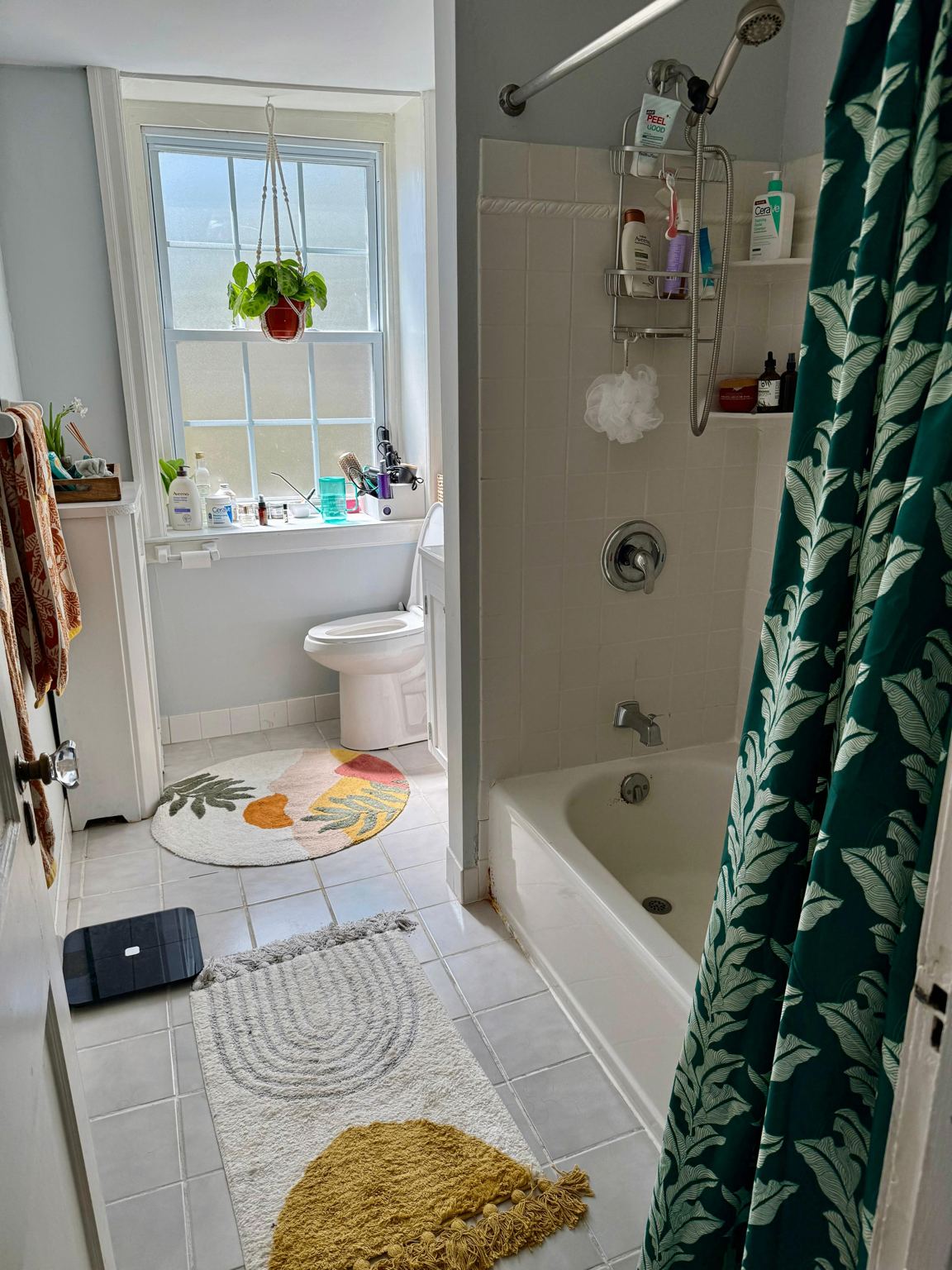 Second-floor bathroom before renovation — dated fixtures, worn tile floor, cluttered surfaces